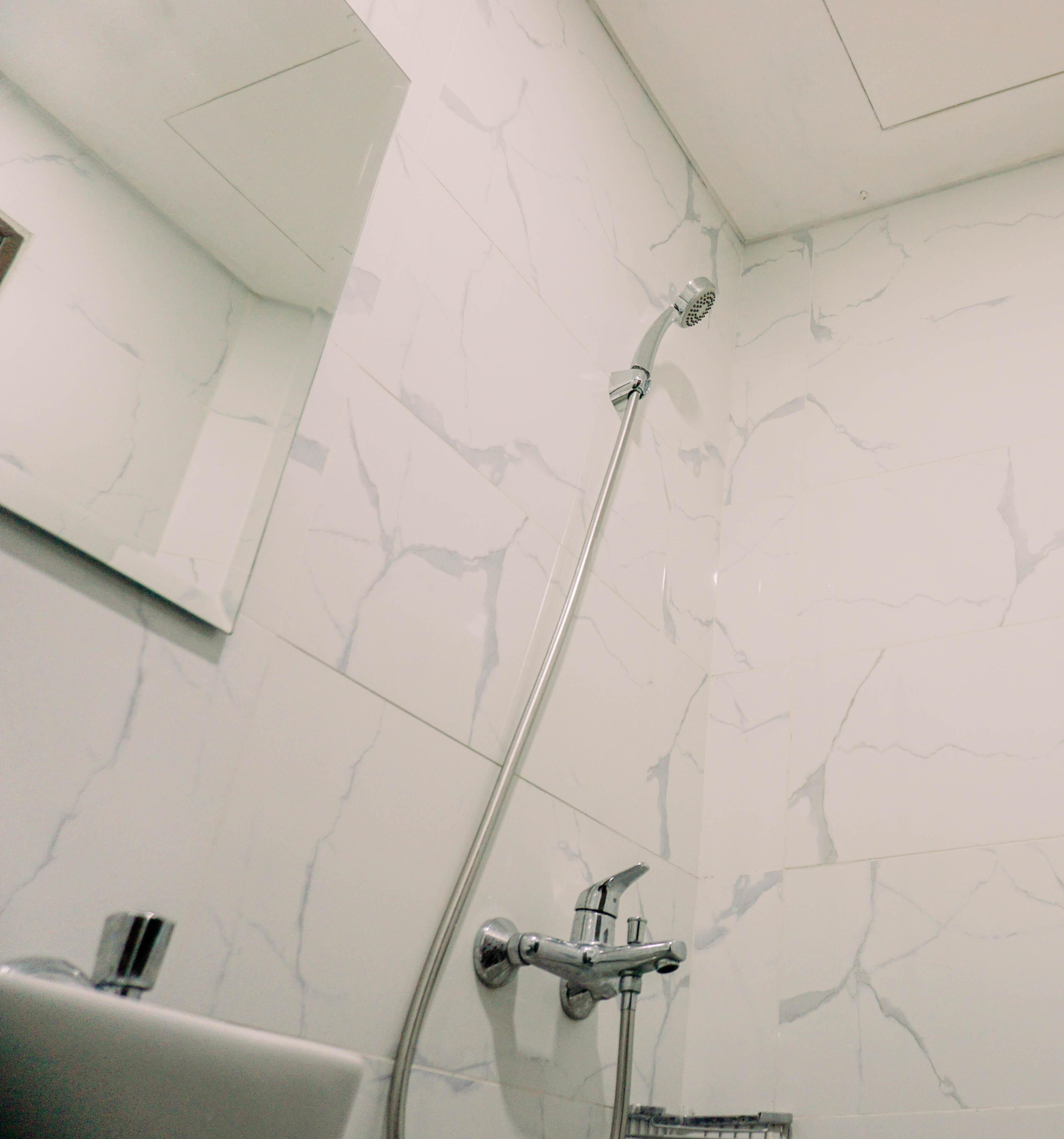 Un baño con ducha, lavabo y espejo.