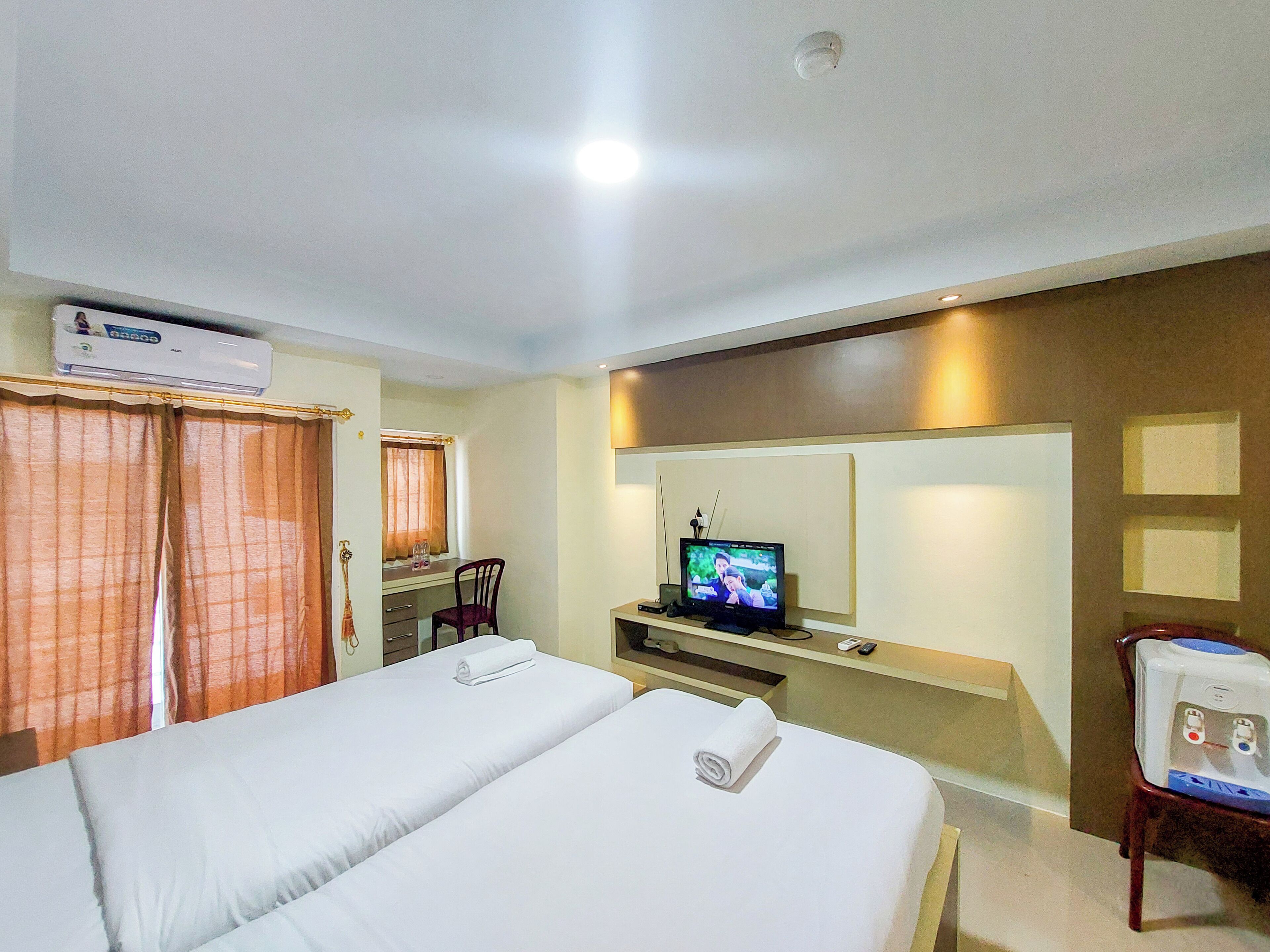 A hotel room with a bed, a desk, a television, and a bedside table.