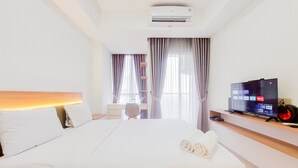 A hotel room with a large bed, a flat-screen TV, a desk, and a chair. - Cozy Living And Nice Studio At Pacific Garden Alam Sutera Apartment (Tangerang)