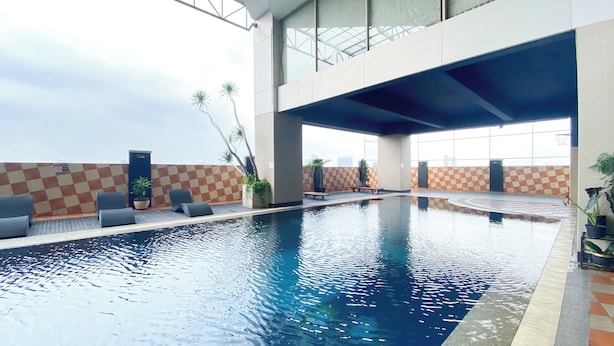 An indoor swimming pool with checkered walls, lounge chairs, and potted plants. - Homey And Comfy Stay 2Br Mangga Dua Apartment (Jakarta)