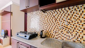 A kitchen with a tiled backsplash, stainless steel sink, and a stove. - Homey And Comfy Stay 2Br Mangga Dua Apartment (Jakarta)