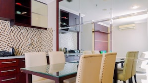 A modern kitchen with a tiled backsplash, a glass dining table, and contemporary chairs. - Homey And Comfy Stay 2Br Mangga Dua Apartment (Jakarta)