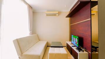 A modern living room with a sofa, a small table, a TV, and a built-in entertainment unit.