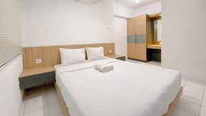 A modern hotel room with a large bed, wooden headboard, and a built-in wardrobe. - Stylish And Spacious Studio At Apartment Jarrdin Cihampelas (Bandung)