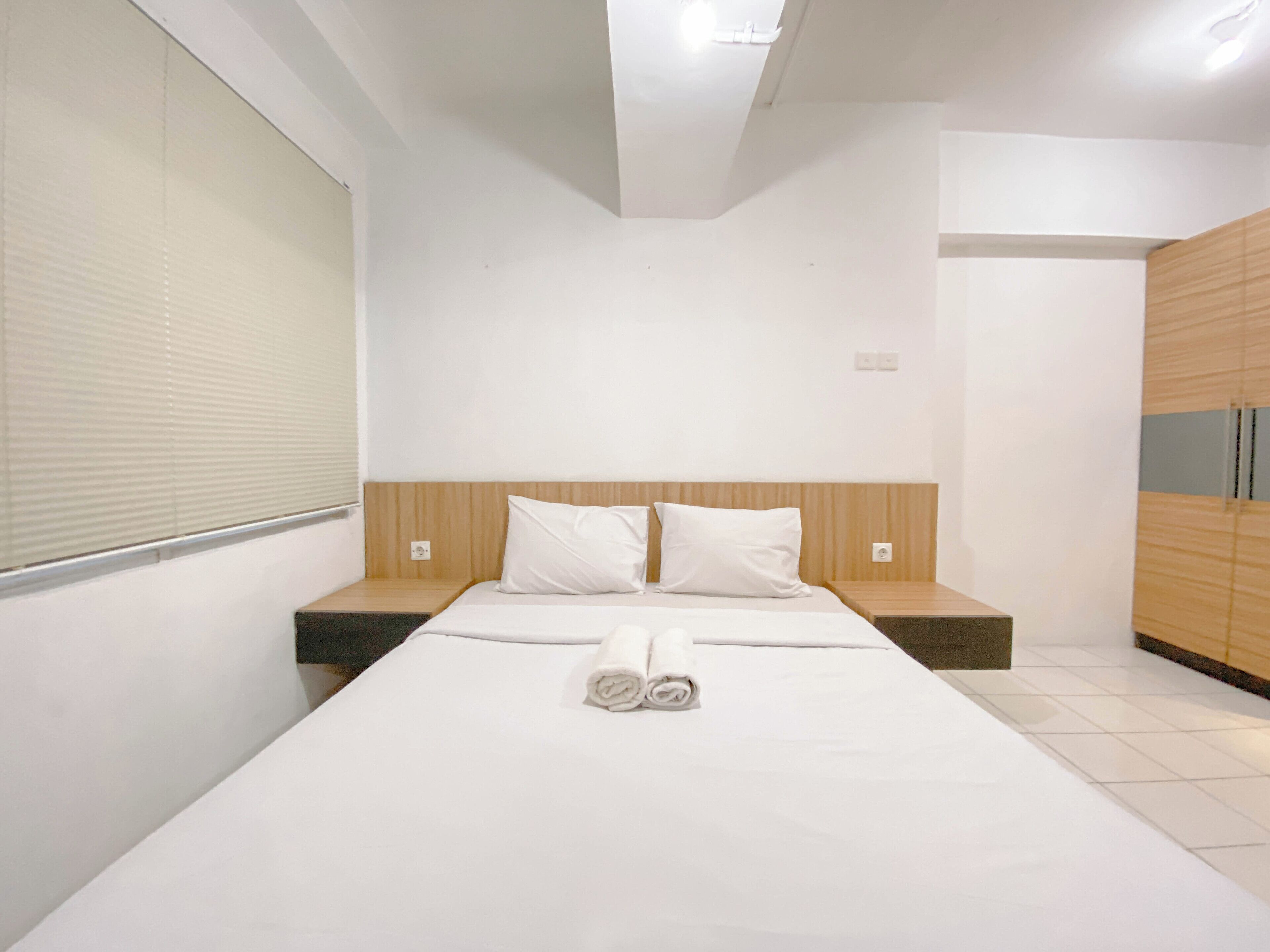 Une chambre d’hôtel moderne avec un grand lit, une tête de lit en bois et une armoire en bois.