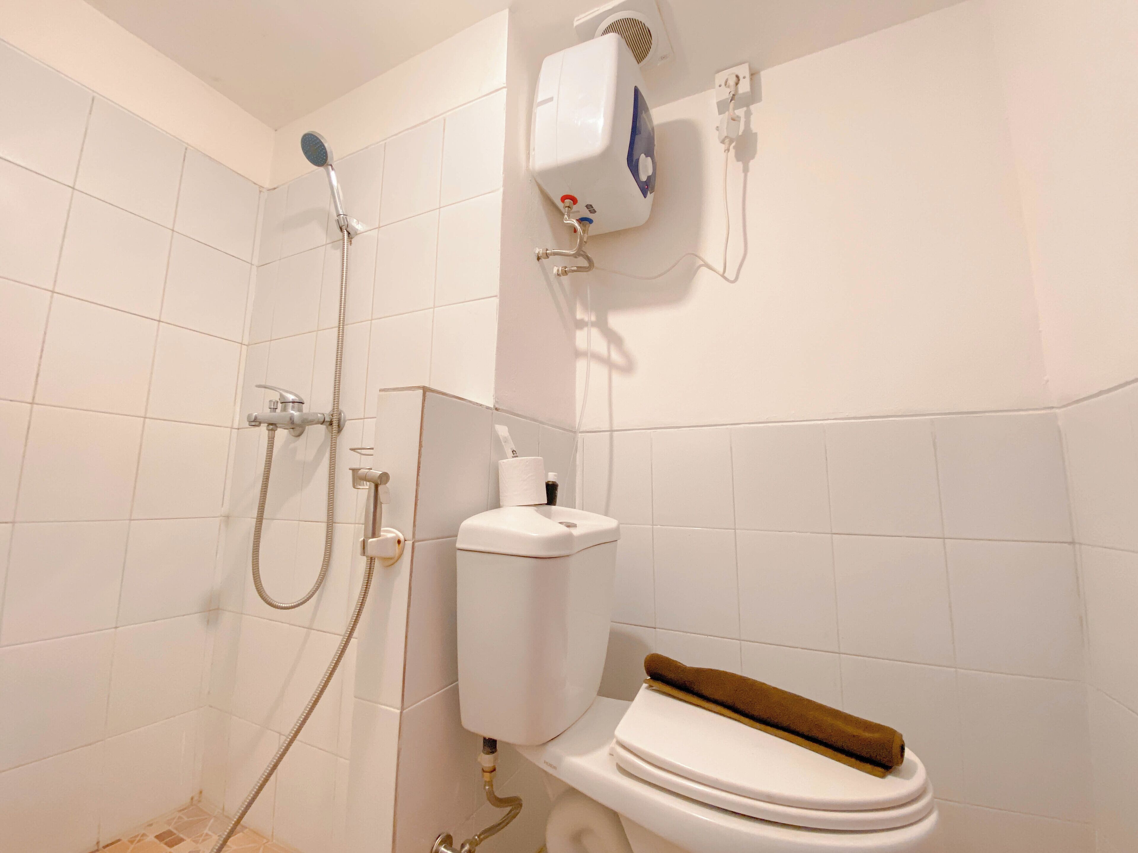 Une salle de bain équipée d’une douche, de toilettes et d’un climatiseur fixé au mur.