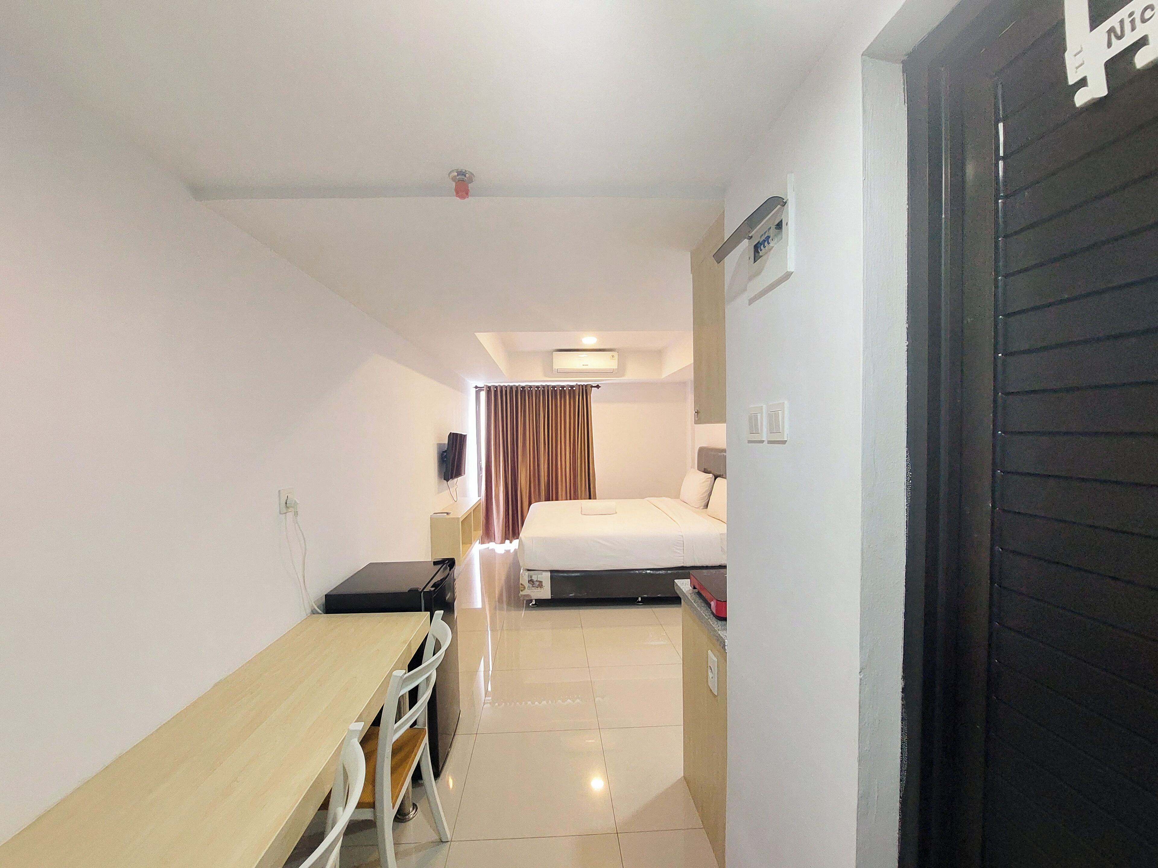 A hotel room with a bed, a desk, a chair, a TV, and a bathroom door.