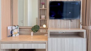 A wooden desk with a flat-screen TV, a small plant, and a framed picture. - Comfort And Modern Look 2Br At Menteng Park Apartment (Jakarta)