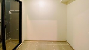 Una habitación con suelo de baldosas, puerta de vidrio y paredes blancas.