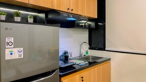 Una cocina con un refrigerador de acero inoxidable, armarios de madera, una encimera negra y una ventana sobre el fregadero.