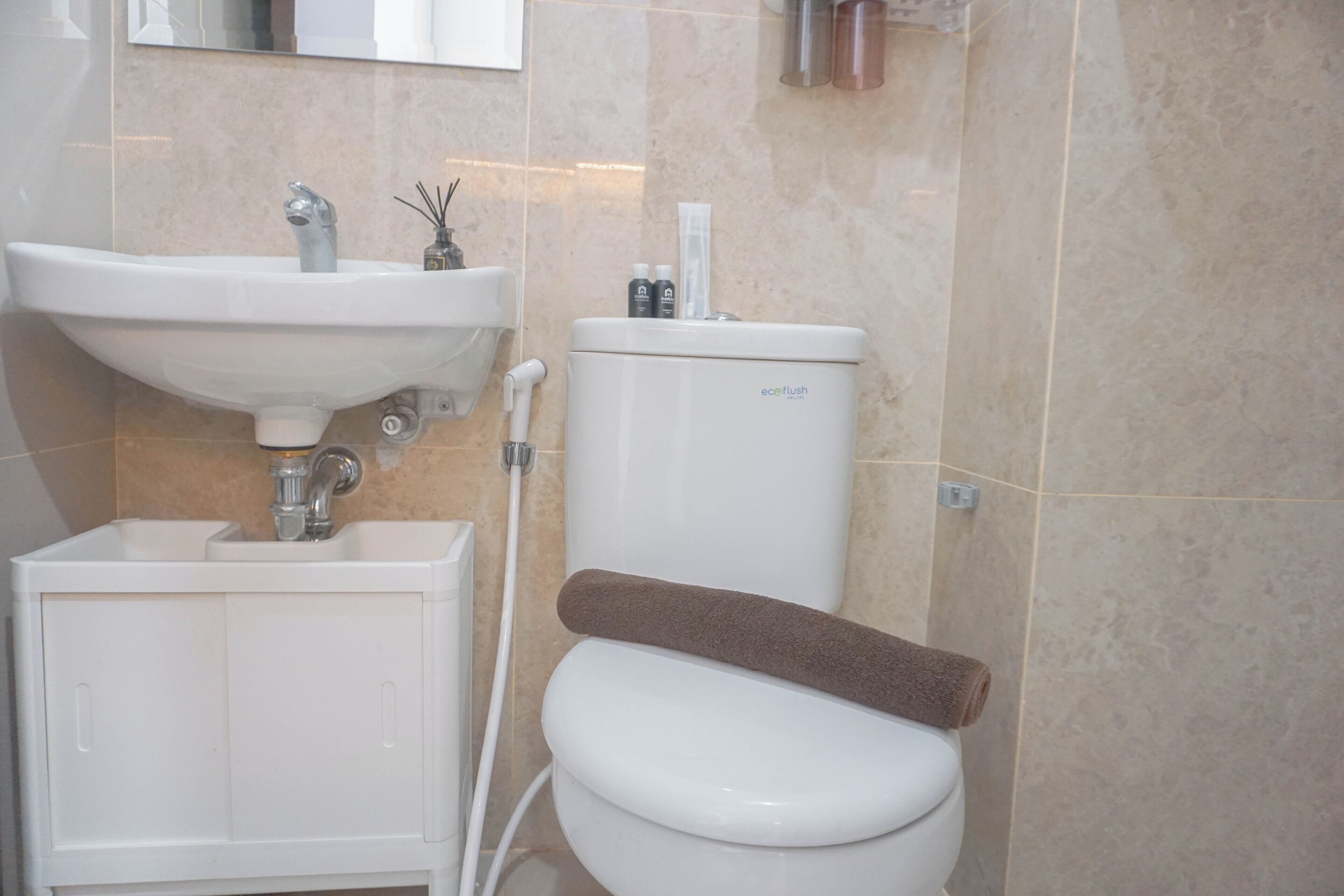 Une salle de bain avec un lavabo blanc, des toilettes et un porte-serviettes.