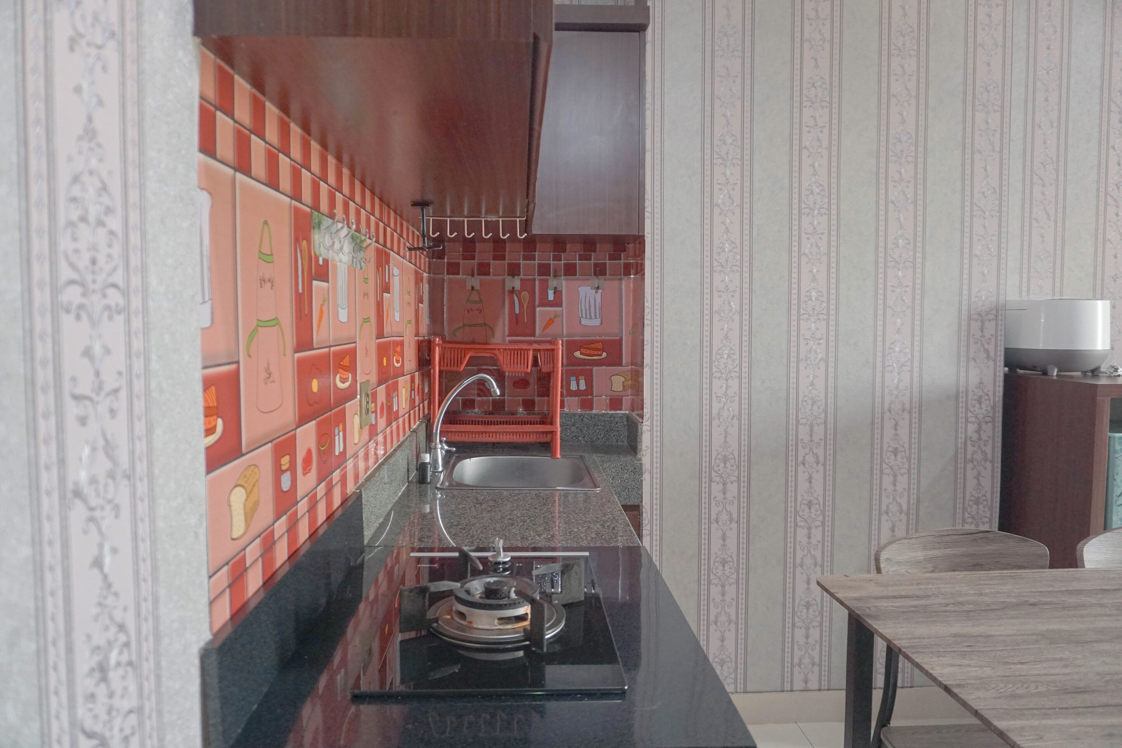 A kitchen with a black countertop, red and white tiled backsplash, and a sink.