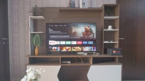 A modern entertainment unit with a flat-screen TV displaying a streaming service interface. - Homey And Best Deal 2Br Transpark Cibubur Apartment (Depok)