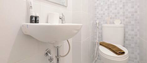 Une salle de bain avec un lavabo blanc, des toilettes et un miroir au-dessus du lavabo.