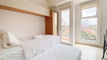 Un dormitorio moderno con una cama grande, un armario y un balcón con vista a la ciudad.
