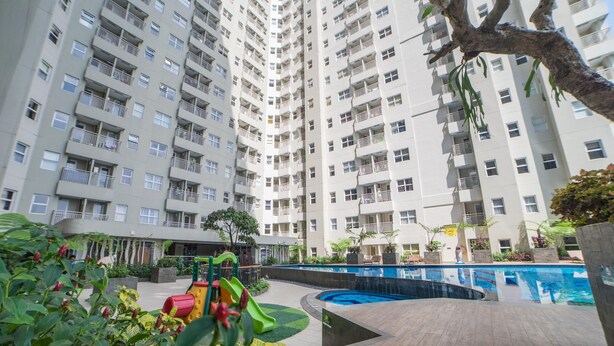 A high-rise residential building with balconies, a swimming pool, and a children's play area. - The Modern Studio Apartment At Parahyangan Residence (Bandung)