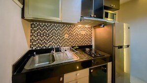 A modern kitchen with a black countertop, stainless steel appliances, and a tiled backsplash. - Homey 2Br At Gp Plaza Apartment (Jakarta)