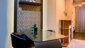 A modern dining area with a glass table, black chairs, and a decorative plant. - Homey 2Br At Gp Plaza Apartment (Jakarta)