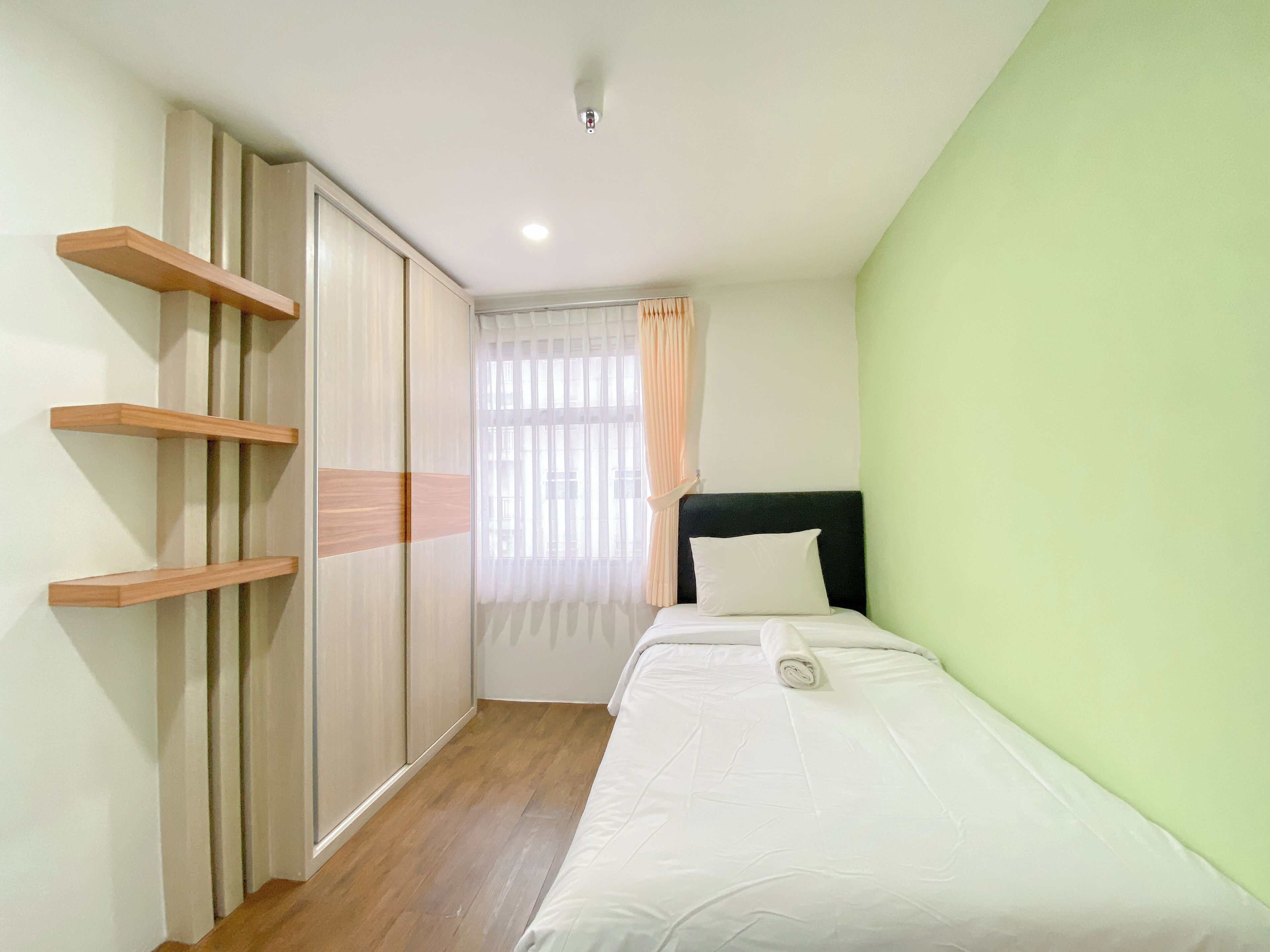 Une chambre à coucher avec un lit, une armoire et une fenêtre avec des rideaux.