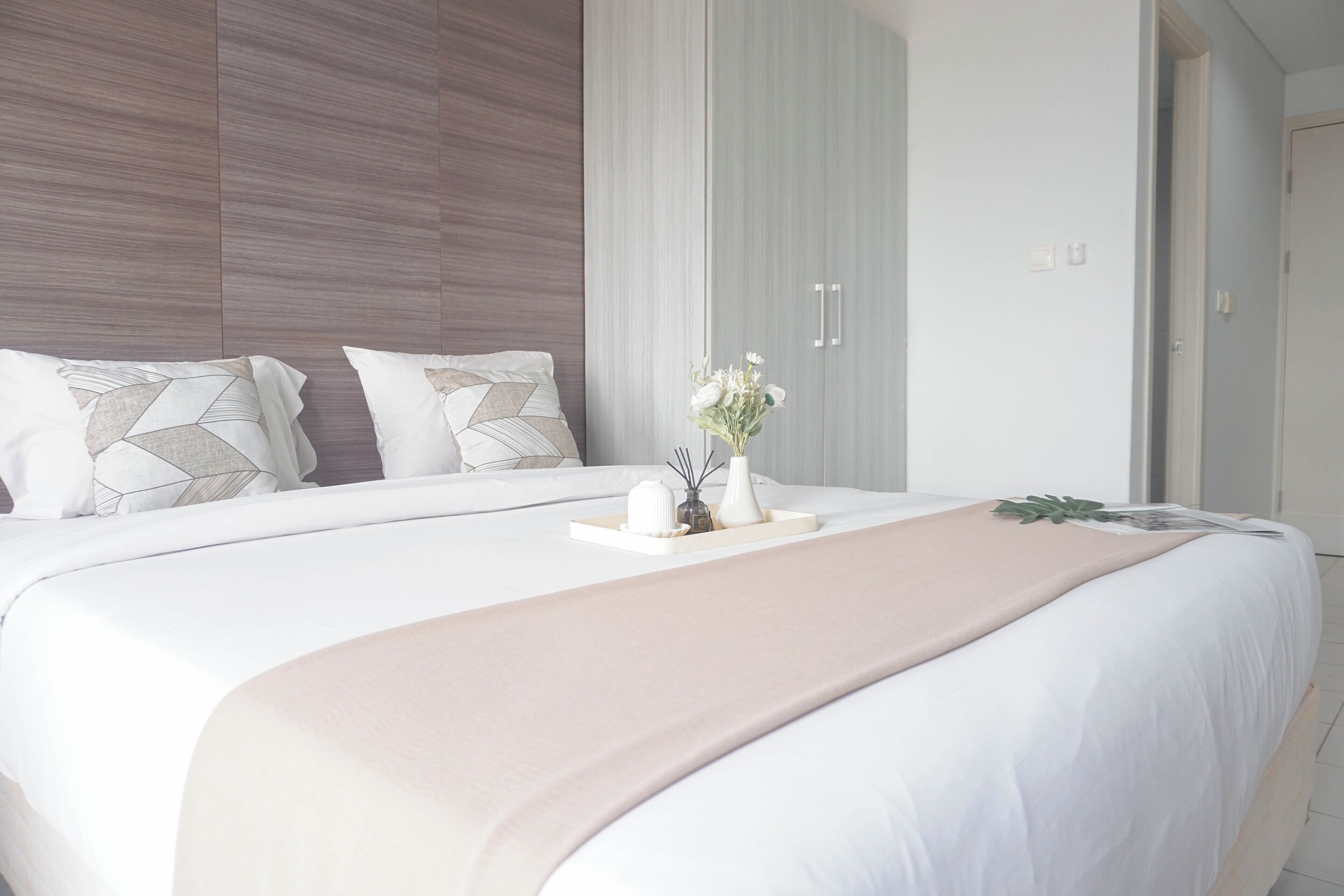A modern bedroom with a large bed, white bedding, and a neutral color palette.