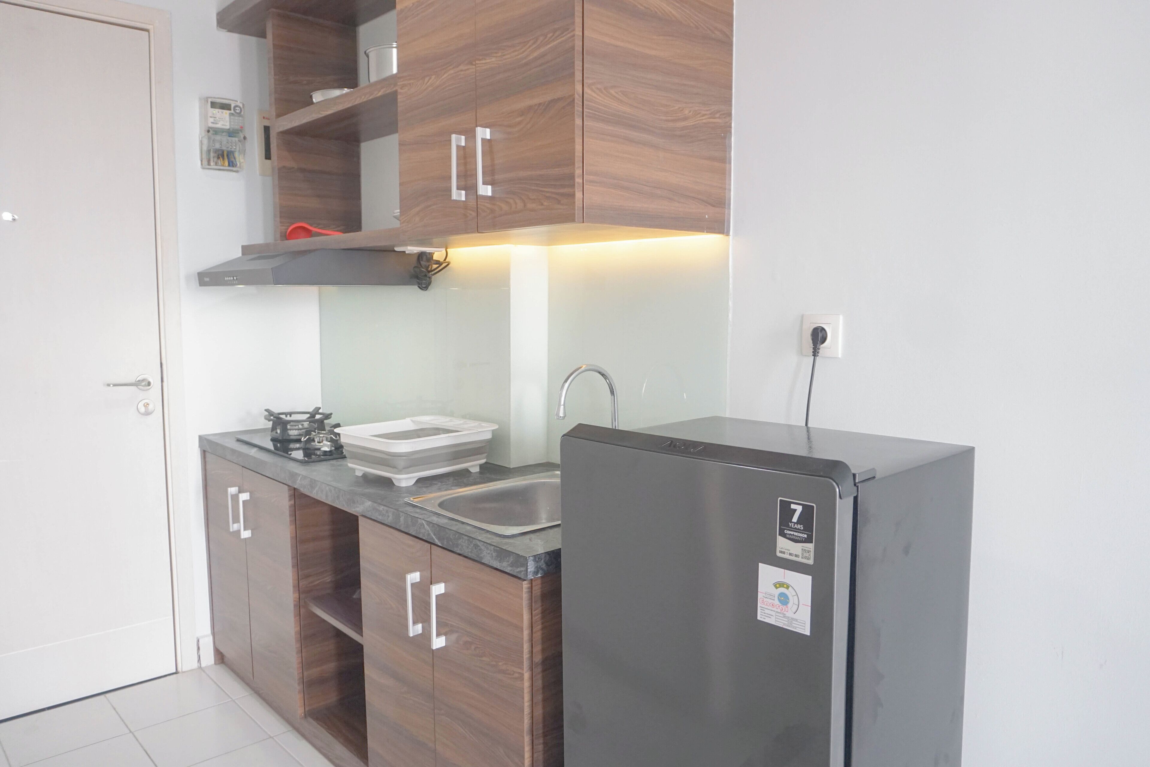 Een kleine keuken met houten kastjes, een roestvrijstalen koelkast en een gasfornuis.