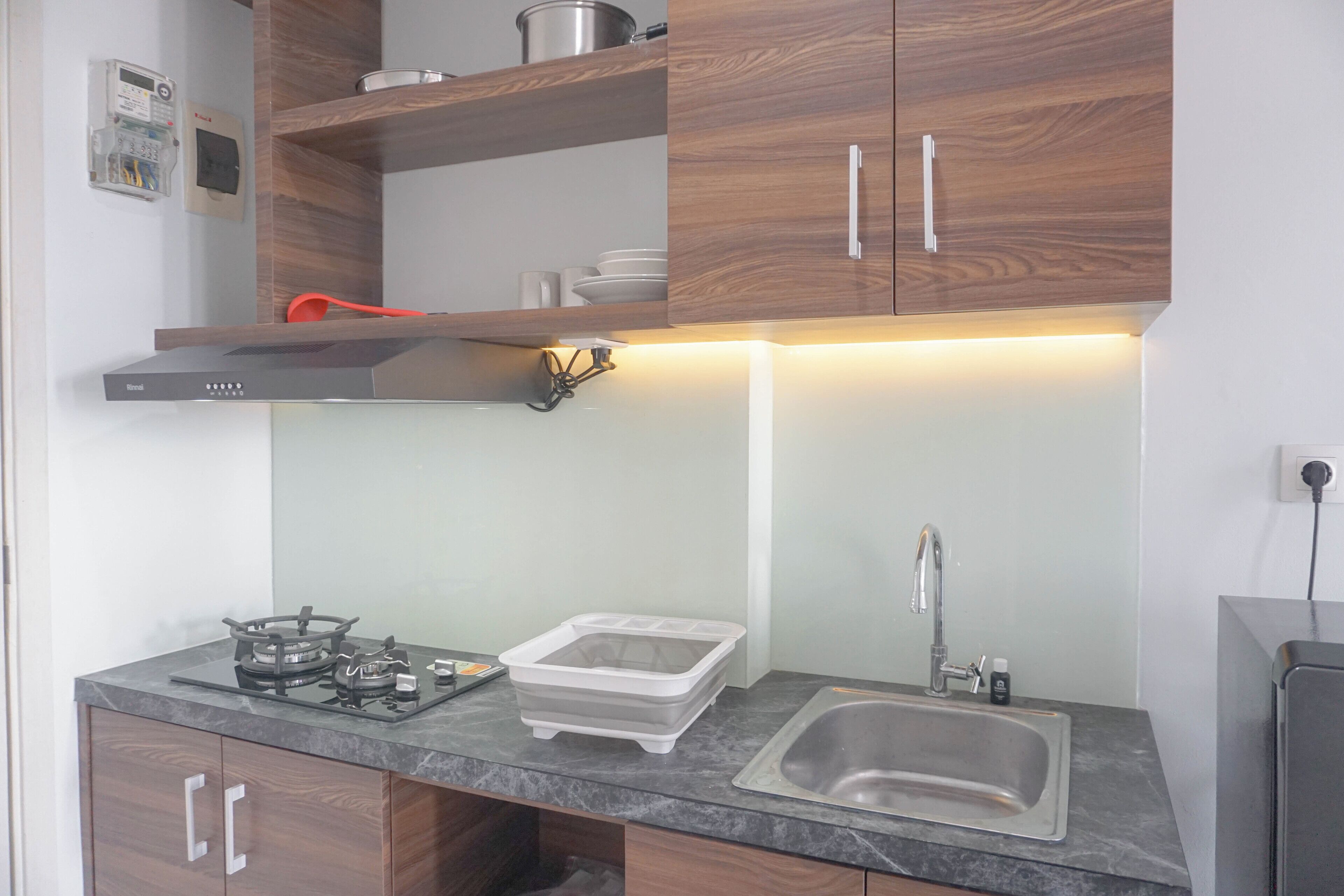 A modern kitchen with a gas stove, a stainless steel sink, wooden cabinets, and a built-in oven.