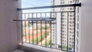 Ein Balkon mit Metallgeländer, einer kleinen Ablagefläche und Blick auf ein Wohngebiet mit Gebäuden und Grünflächen.