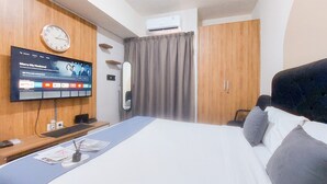 Ein Hotelzimmer mit Bett, Wandfernseher, einer Uhr und einem Holzschrank.