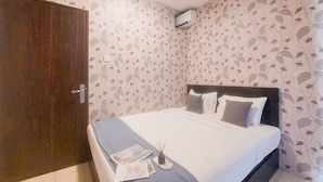 Un dormitorio con cama, armario y papel tapiz con motivos florales.