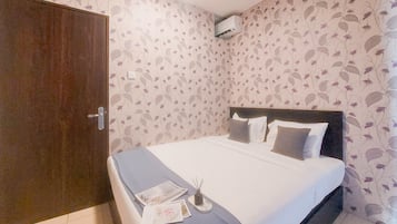 Ein Schlafzimmer mit einem Bett, einem Kleiderschrank und blumigem Wandpapier.