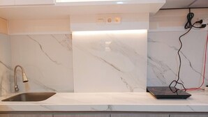 A modern kitchen with a marble backsplash, a stainless steel sink, and wooden cabinets.