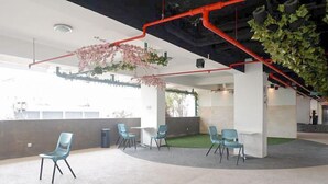 A modern office space with a curved seating area, white walls, and exposed ductwork. - Compact And Restful Studio At Pavilion Permata Apartment (Surabaya)