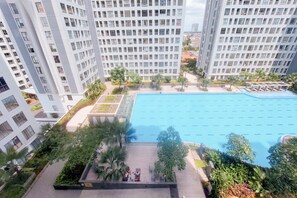 Un edificio residencial alto con piscina y zonas verdes circundantes.