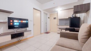 Una sala de estar moderna con televisor de pantalla plana, un sofá, una mesa de centro y una cocina al fondo.