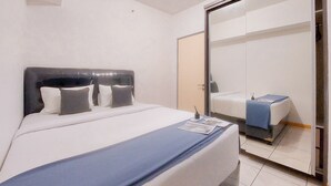 Una habitación de hotel con una cama grande, una mesita de noche, un espejo y un armario.