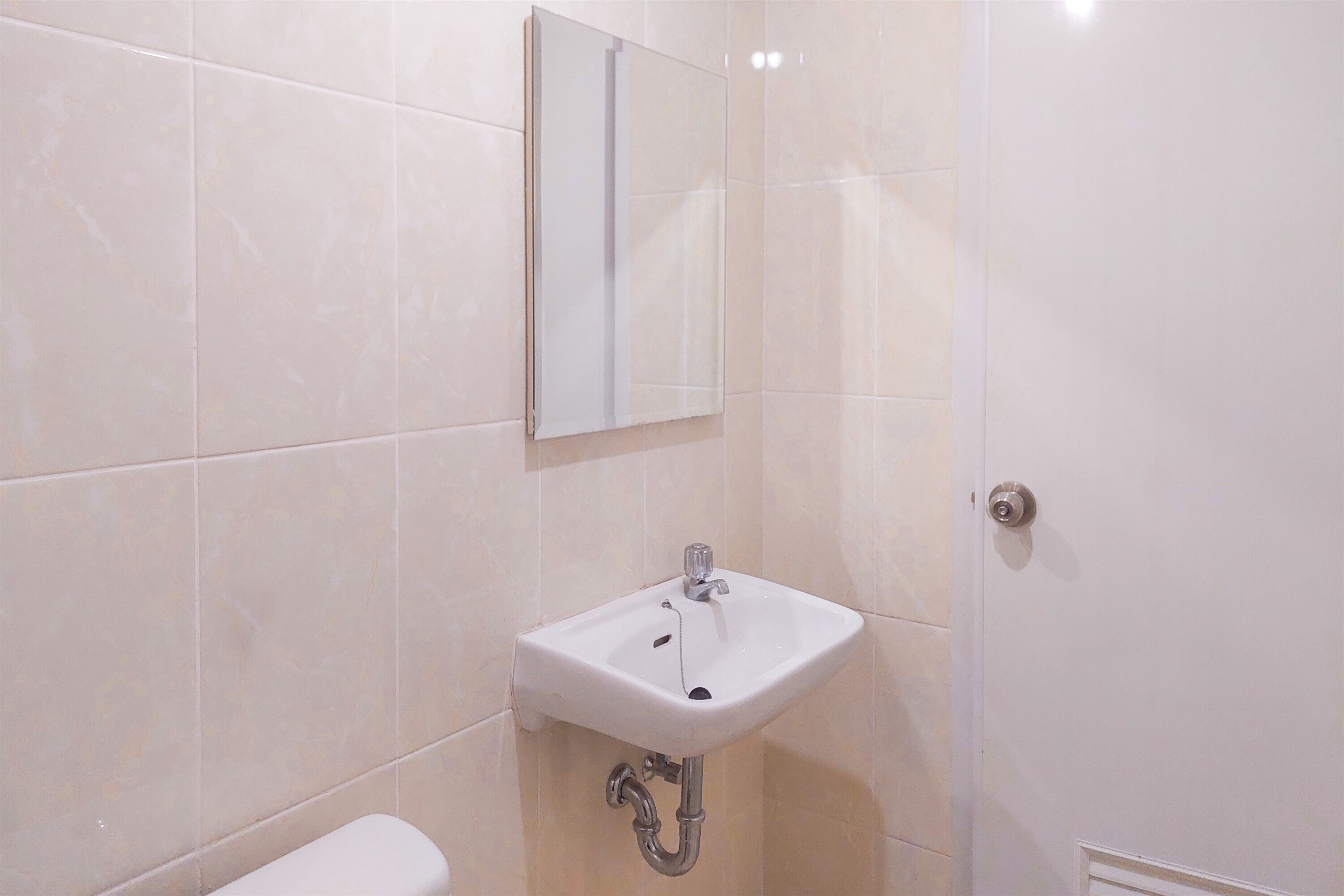 A bathroom with a white sink, a mirror, and a toilet.