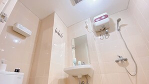 Un baño con inodoro, lavamanos, espejo, ducha y toallero.