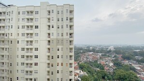 Un edificio residencial alto con varios balcones y vistas a una zona urbana densamente poblada, con edificios y áreas verdes.