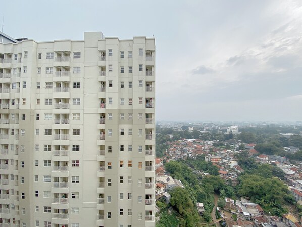 Un edificio residencial alto con varios balcones y vistas a una zona urbana densamente poblada, con edificios y áreas verdes.