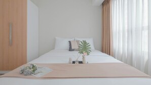 Une chambre bien rangée, avec un lit, une armoire et une fenêtre avec des rideaux.