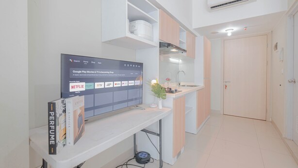 Une cuisine moderne dotée d’un téléviseur encastré affichant l’interface de Google Play Films et séries, d’un plan de travail blanc et d’une petite plante.