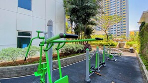Des appareils de musculation en plein air sont installés dans une cour, avec un bâtiment en arrière-plan.