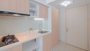 Une cuisine moderne avec des meubles de couleur bois clair, un évier en acier inoxydable et une cuisinière à gaz.