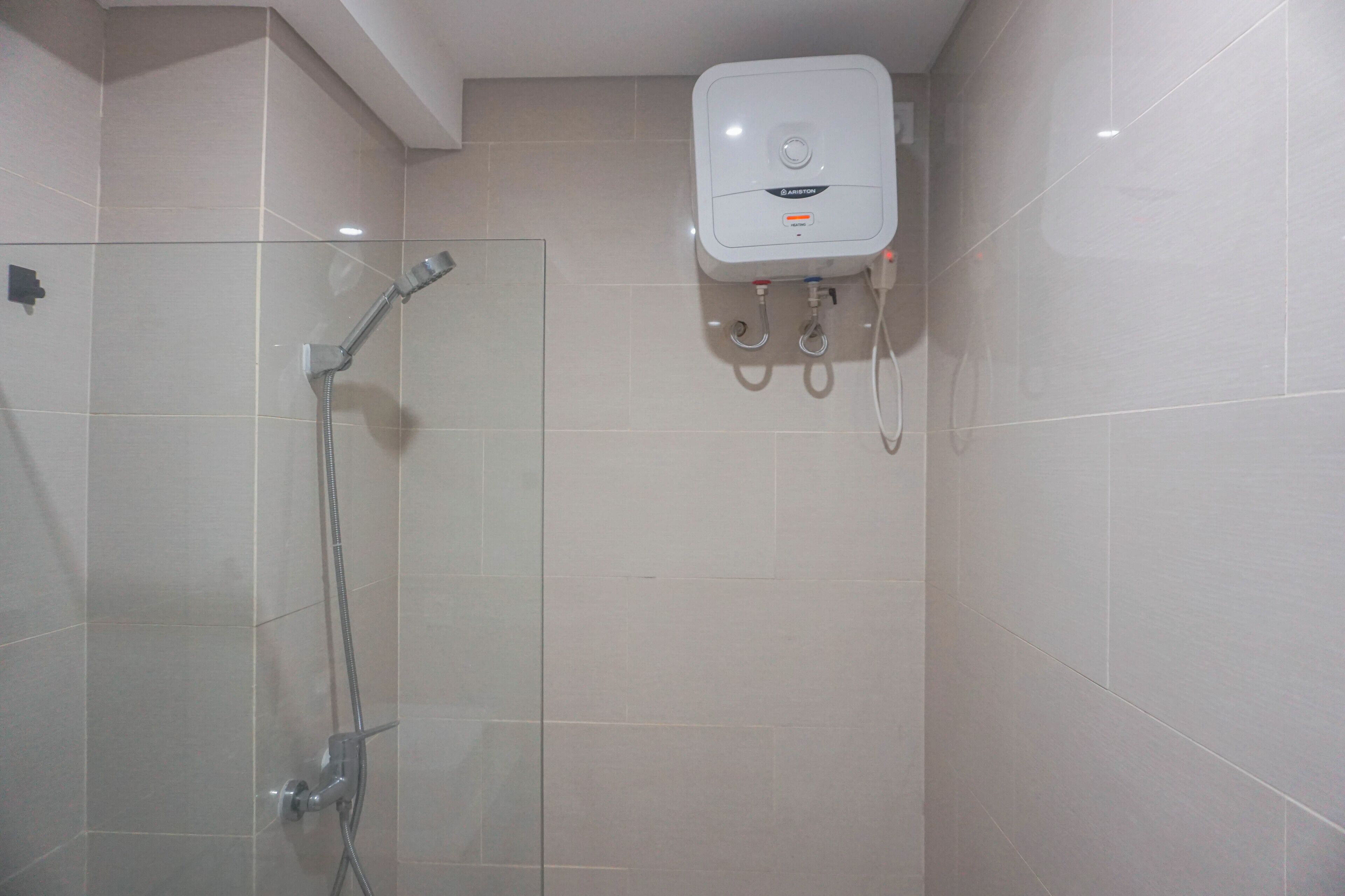 A modern bathroom with a glass shower enclosure, a handheld showerhead, and a wall-mounted water heater.