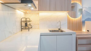 A modern kitchen with a white countertop, a stainless steel sink, and wooden cabinets. - Cozy And Spacious Studio At Daan Mogot City Apartment (Jakarta)