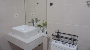 A modern bathroom with a white sink, mirror, and a towel rack. - Cozy And Spacious Studio At Daan Mogot City Apartment (Jakarta)