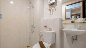 A bathroom with a toilet, shower, and sink.
