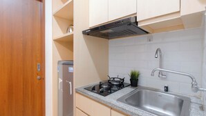 A kitchen with a stove, sink, cabinets, and a door.