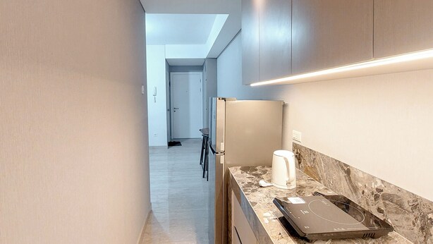 A modern kitchen with a marble countertop, a coffee maker, and a laptop. - Tranquil Space 1Br Apartment At Podomoro City Deli Medan (Medan)