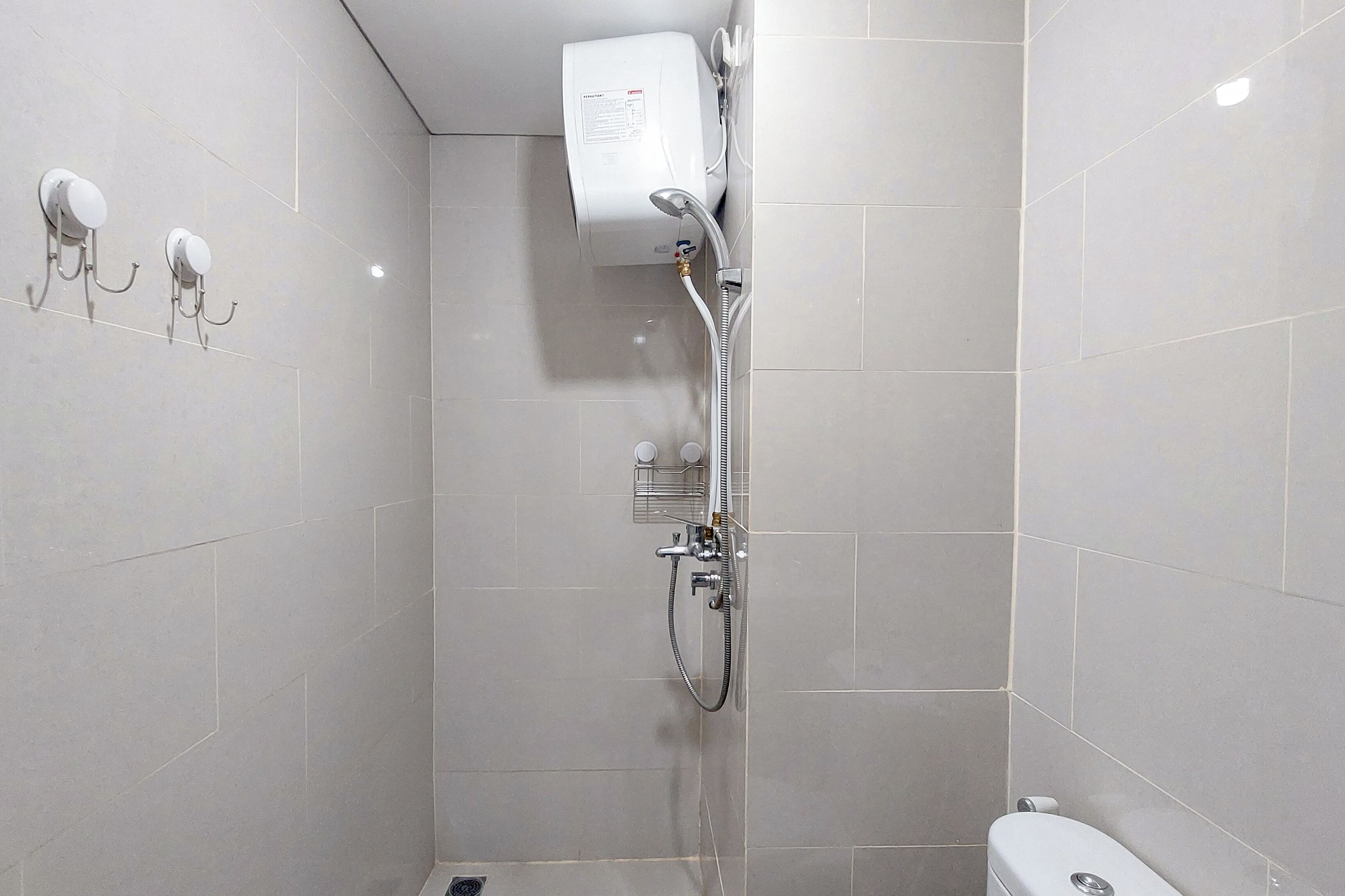 Un baño pequeño y moderno con ducha, inodoro y ganchos para toallas en la pared.